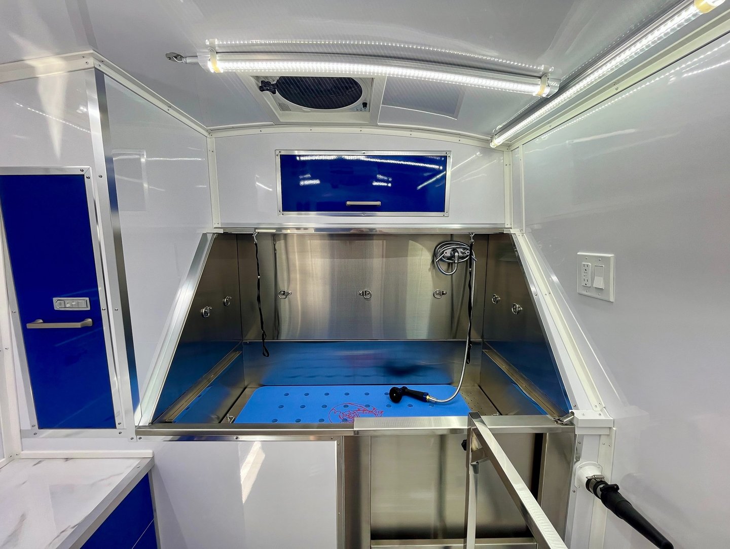 Professional stainless steel dog grooming bathtub inside a clean, fully equipped mobile grooming van
