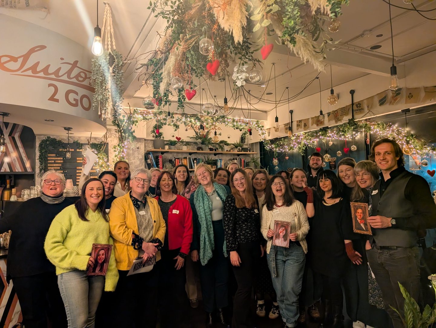 a group of people smile for a photograph after having fun at a themed Traitors party.