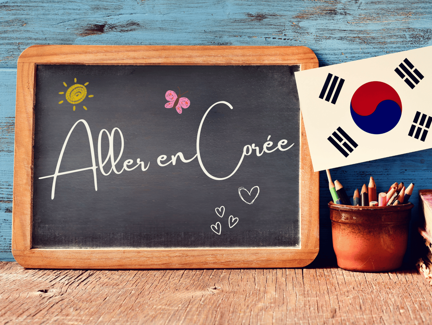 Tableau noir posé sur une table en bois avec l’inscription manuscrite  Aller en Corée