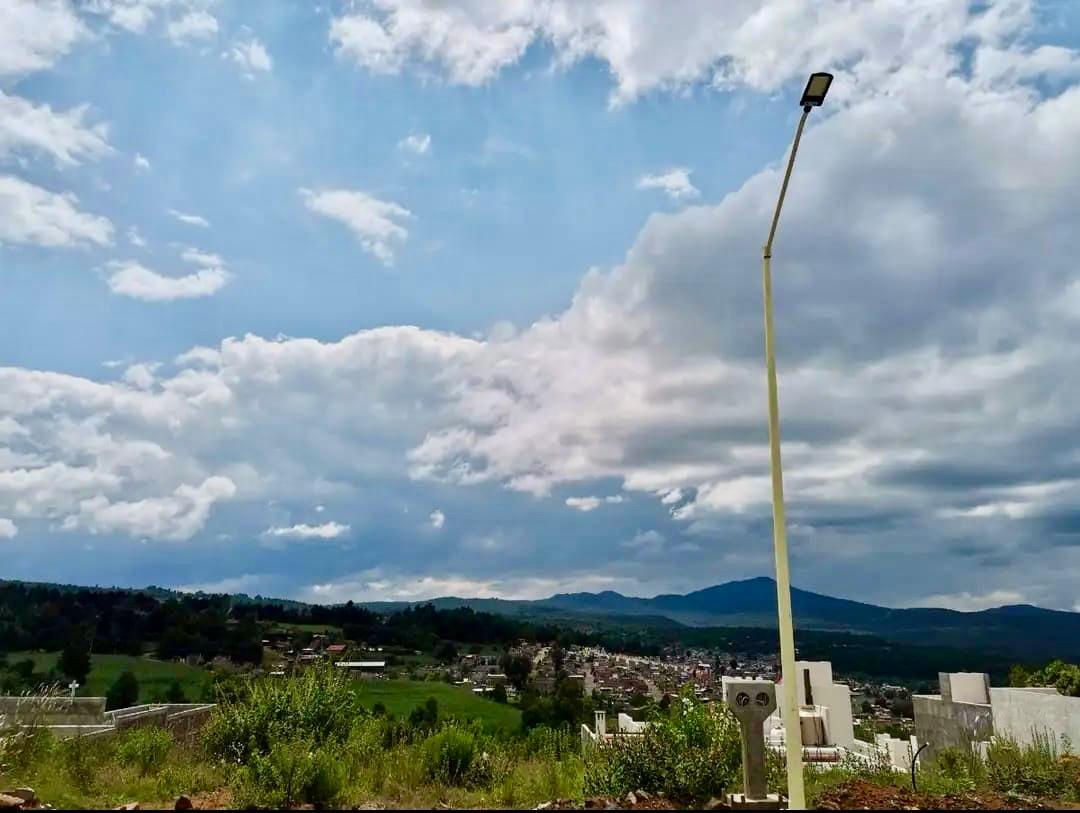 Panoramic landscape view of a rural village under a blue sky with white clouds and a tall street light.