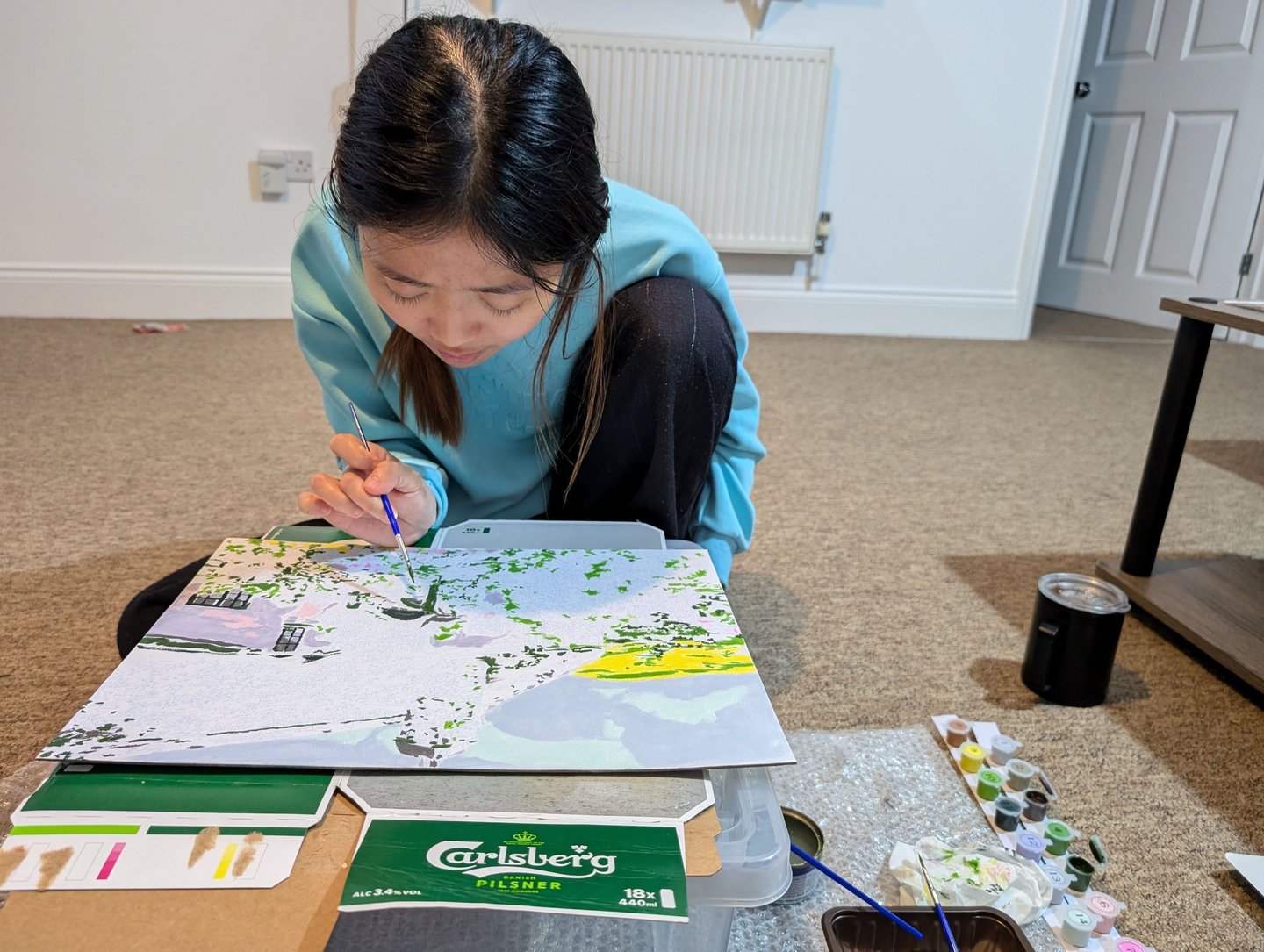 lady in blue dress sitting and painting carefully
