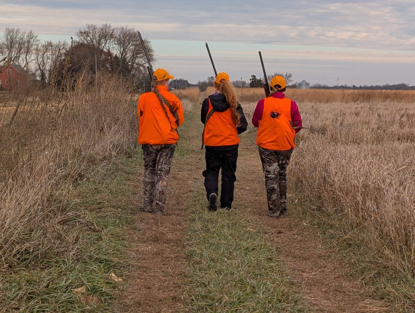Three women hunters walking in a field.