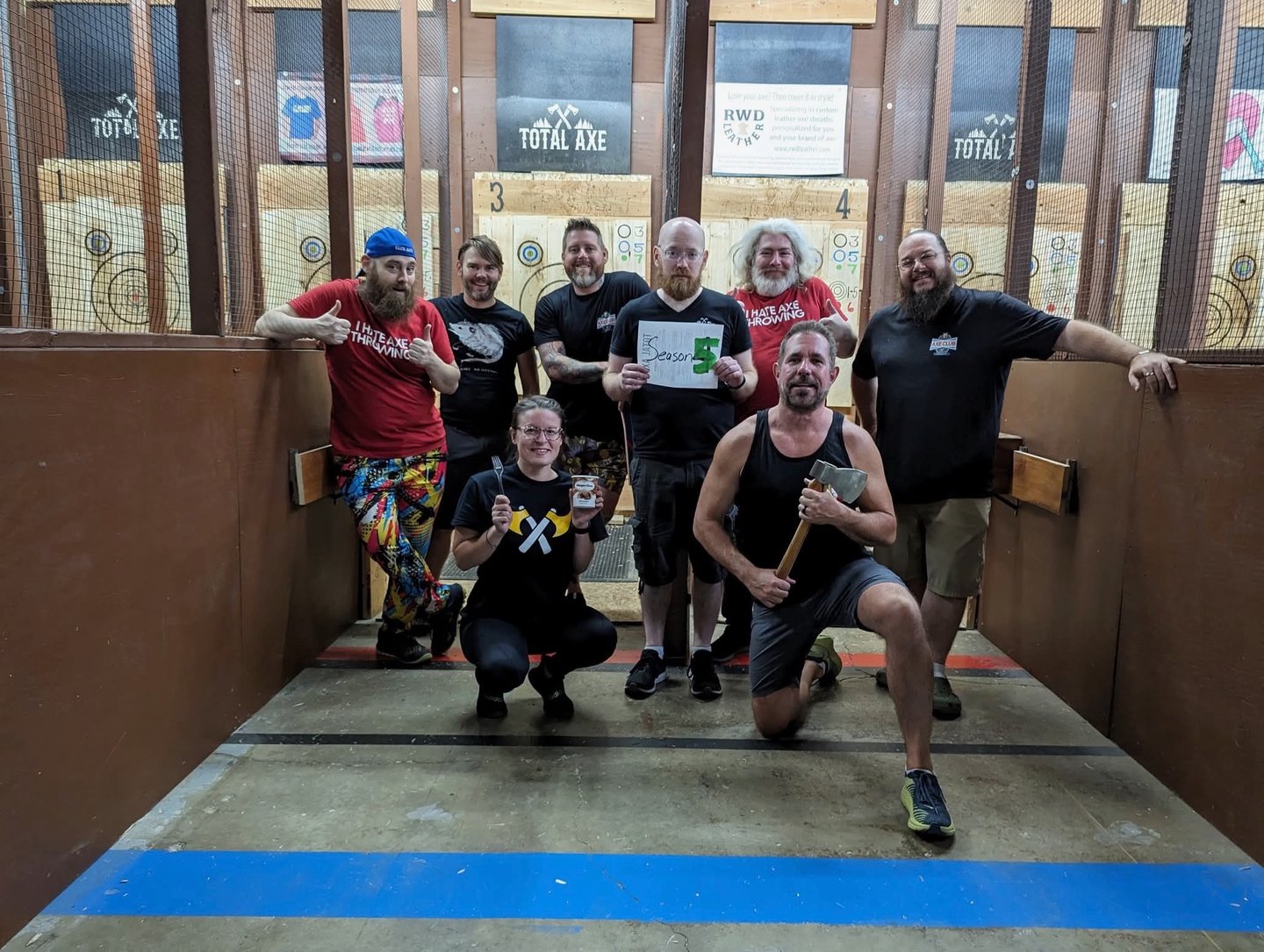 happy but tired group in an axe throwing arena