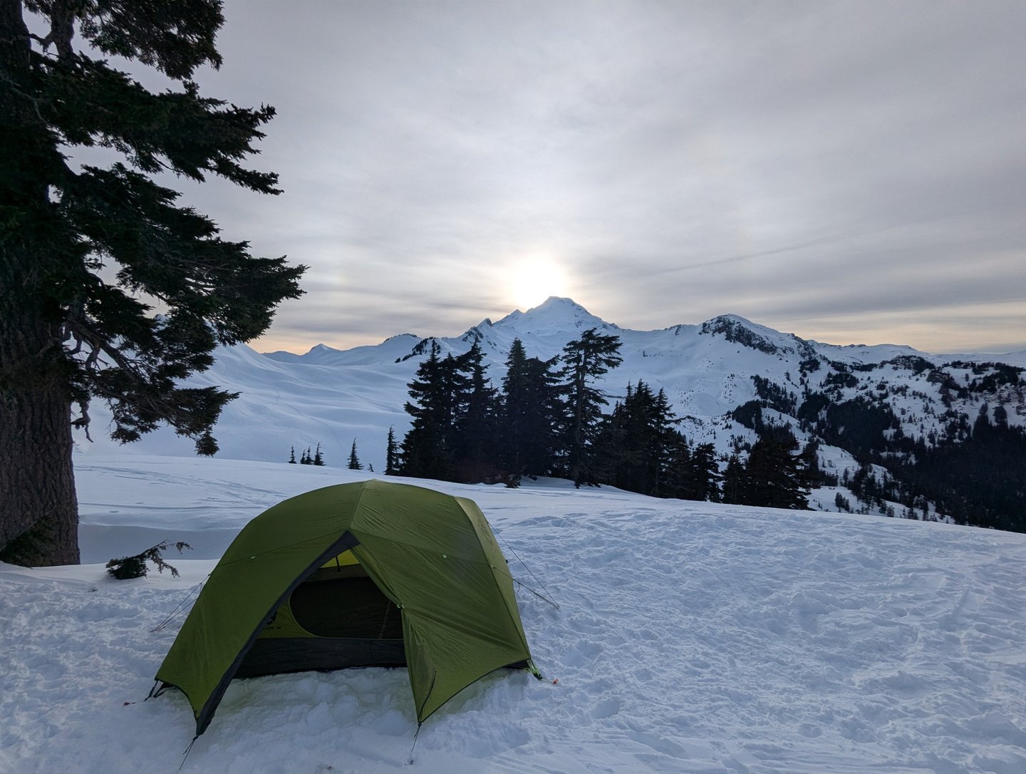 NEMO Dagger 3p tent set up for winter backpacking in the snow with a mountain sunset background.