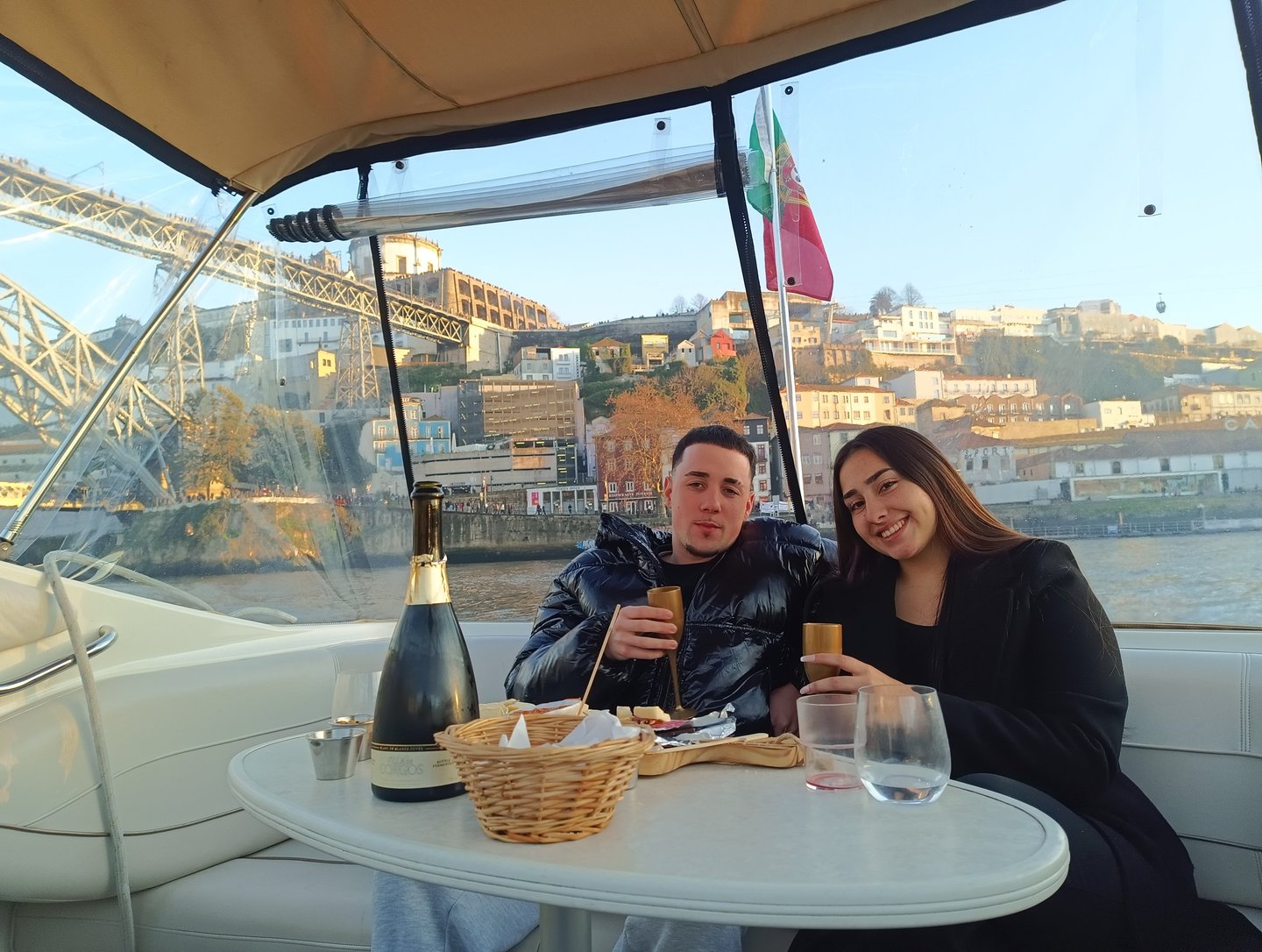 A couple enjoying a private boat tour in Porto with champagne and views of the Dom Luís I Bridge.
