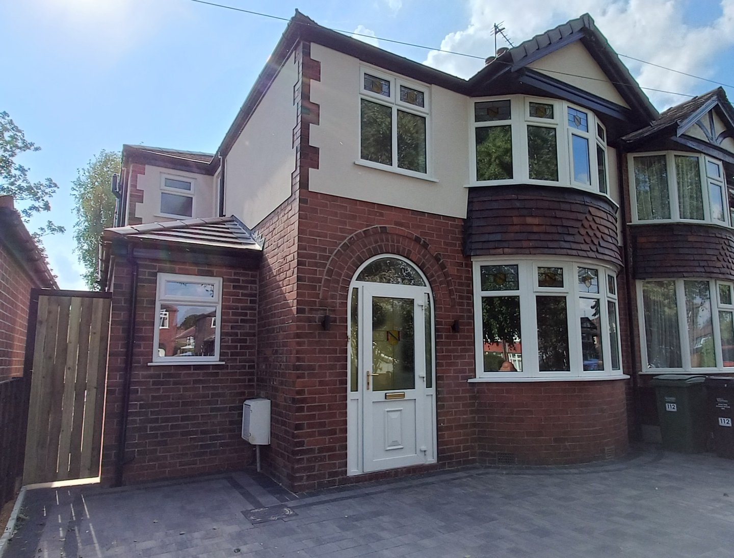 Modern semi-detached red brick house with white uPVC windows and a bay window on a paved driveway.