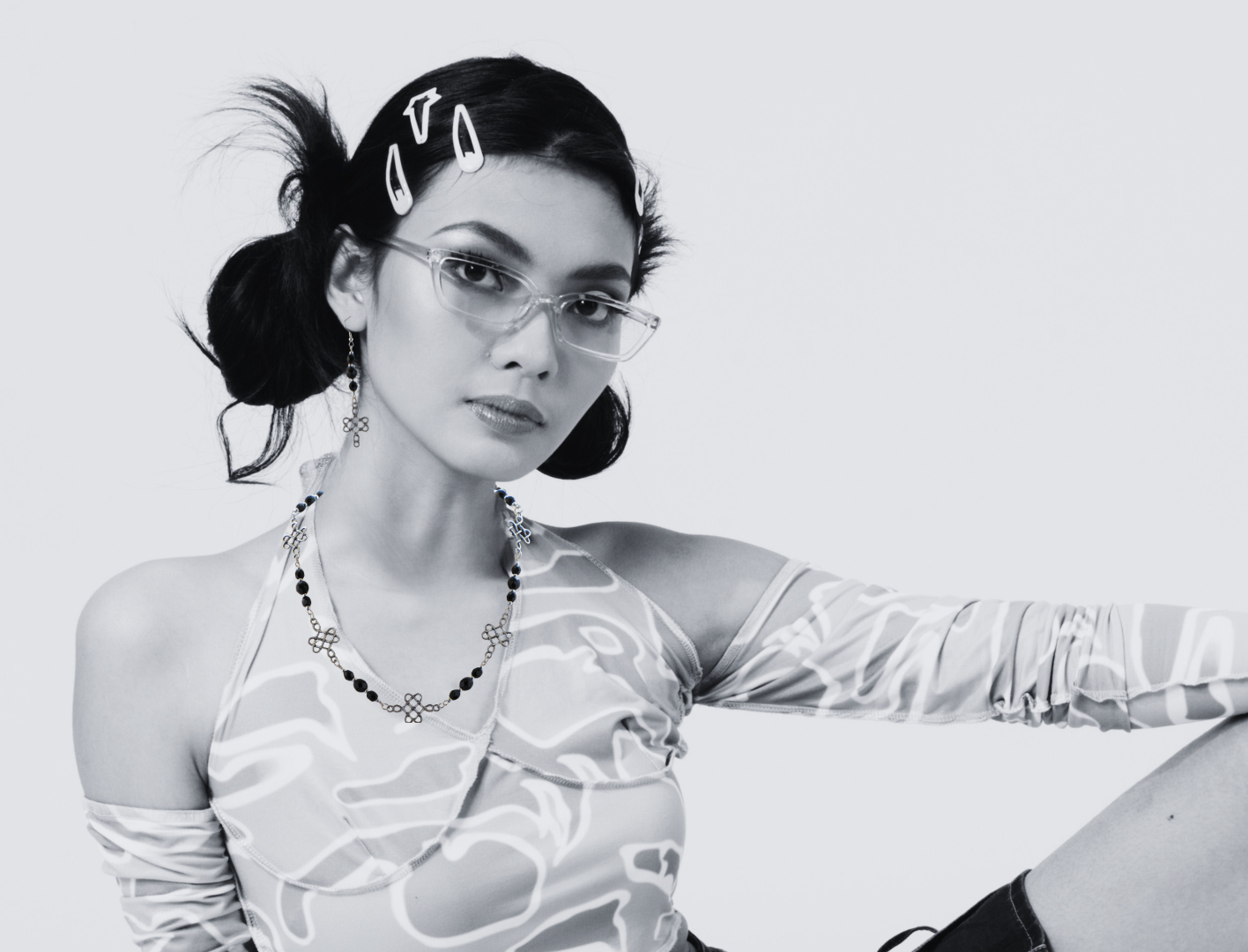 Stylish woman wearing glasses, hair clips, a patterned halter top and necklace and earrings set