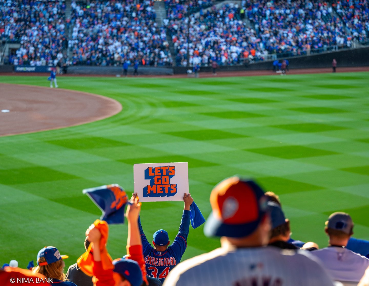 fans cheering and waving 'lets go mets' signs and rally towels at citifield during nlcs game 5