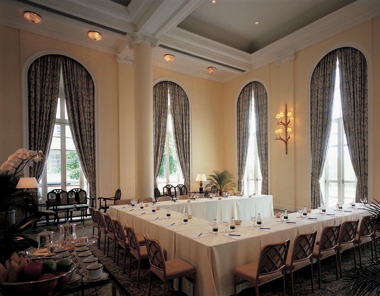 Elegant conference room setup with u-shaped tables and arched windows for a luxury corporate meeting.