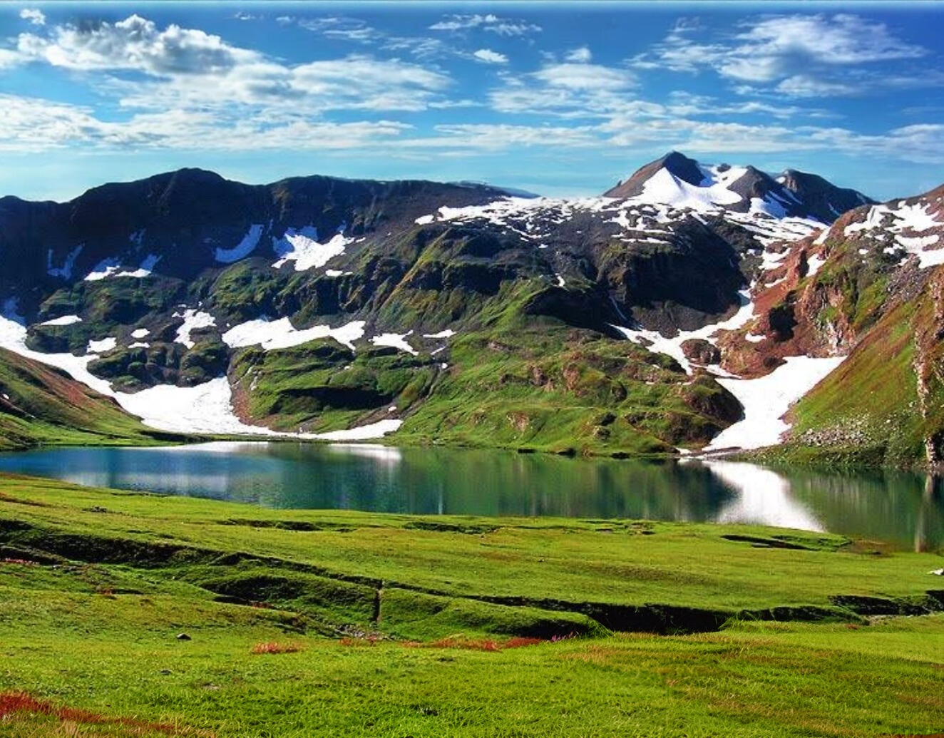 a mountain scene with Ansoo lake and mountains in the background