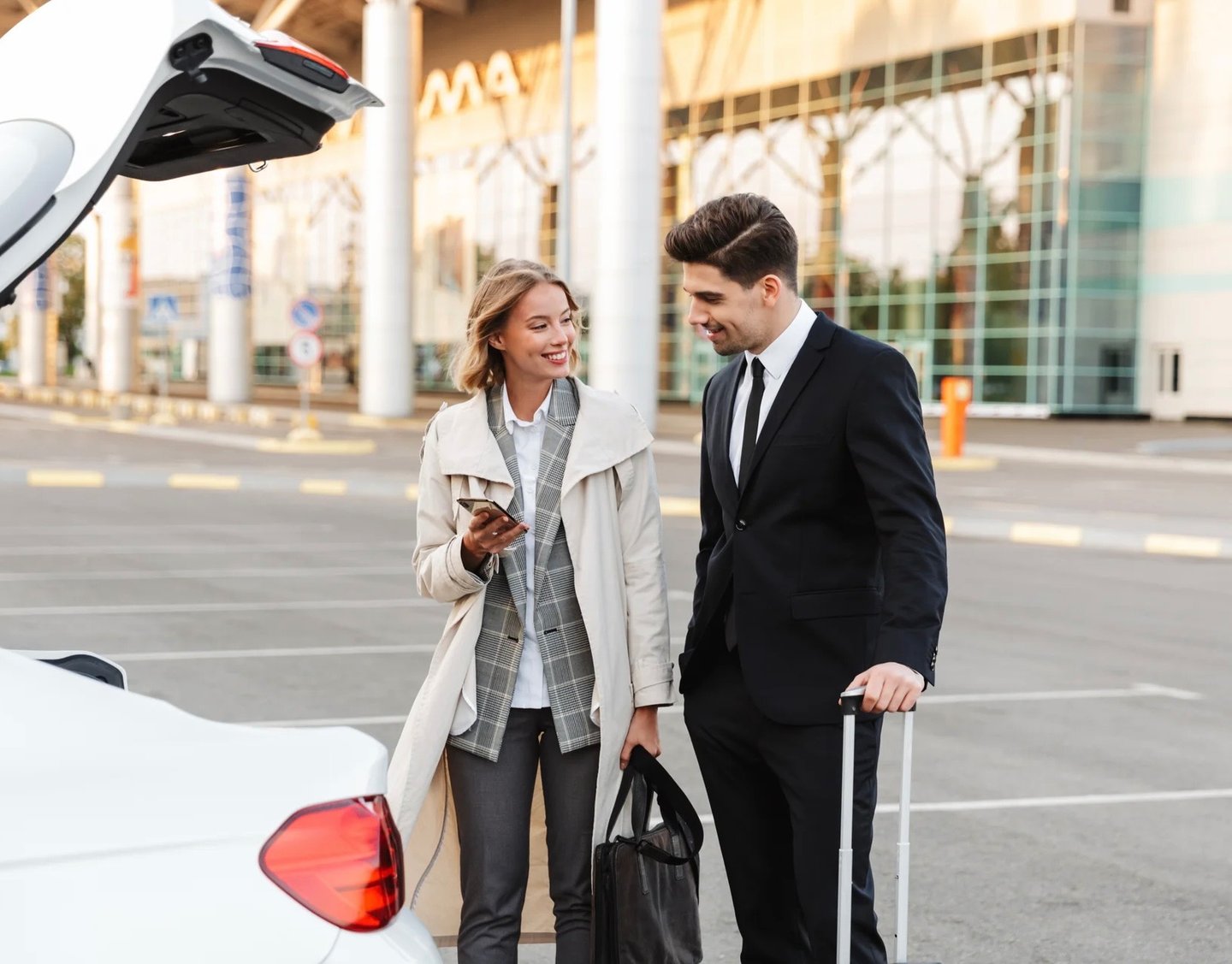 a man and woman standing in front of a car