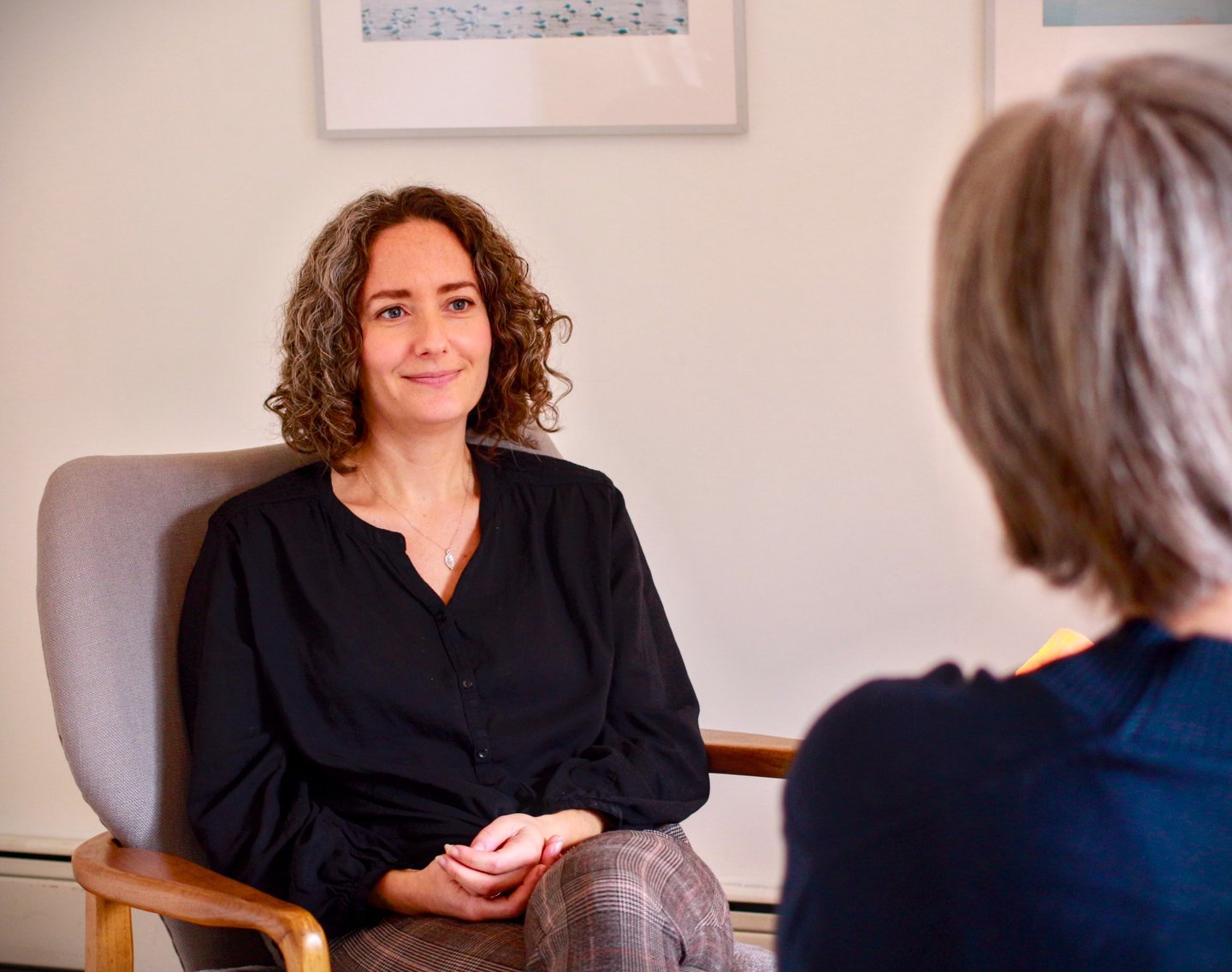 Female therapist with a relaxed and calm demeanor sits across from client 