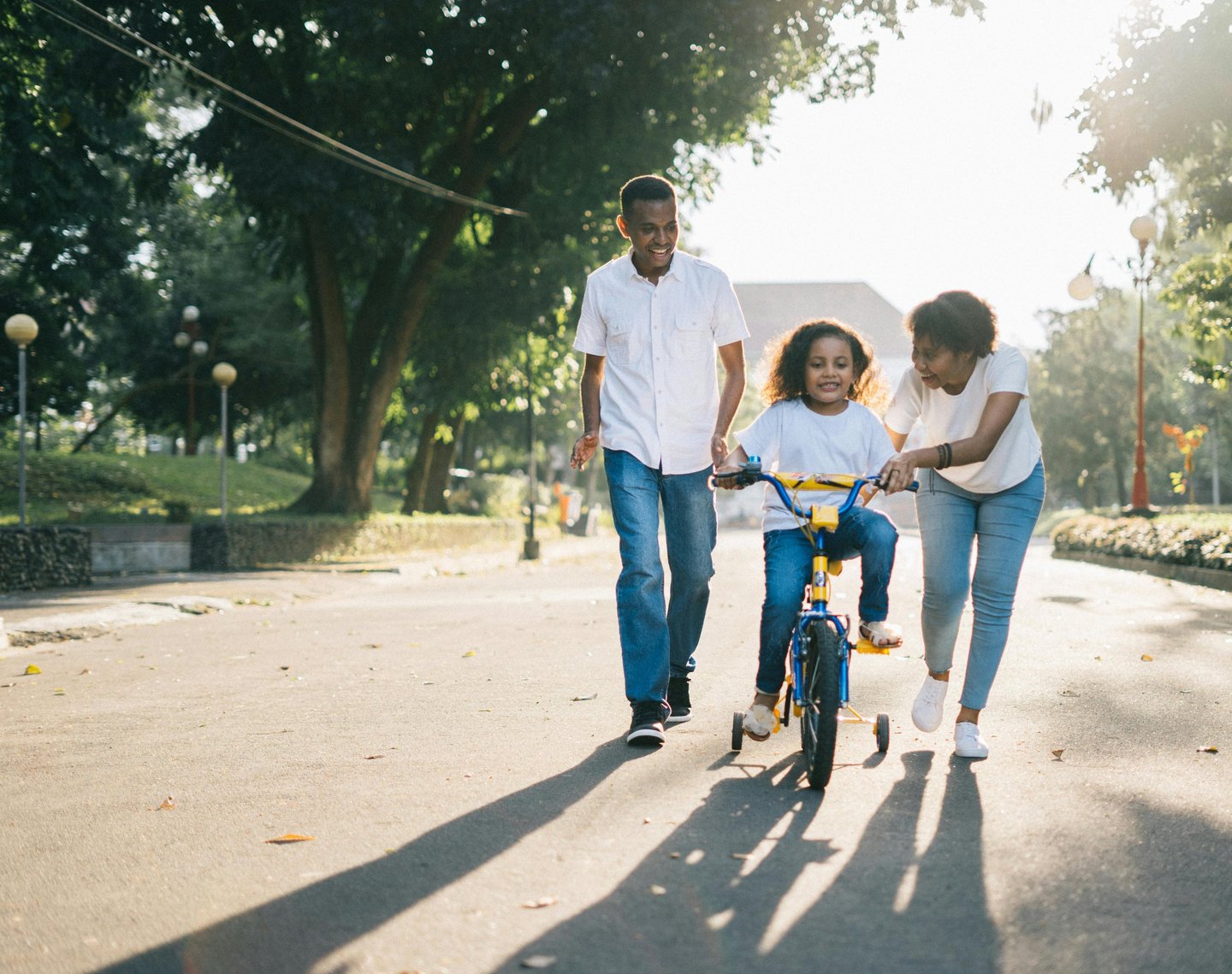 family helping child ride a bike