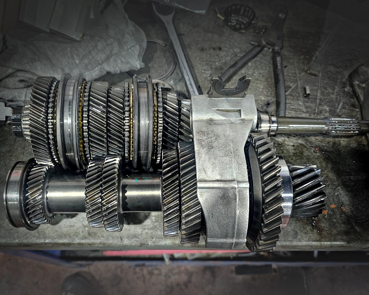 Internal manual transmission gears and shafts assembly on a mechanical repair workbench.