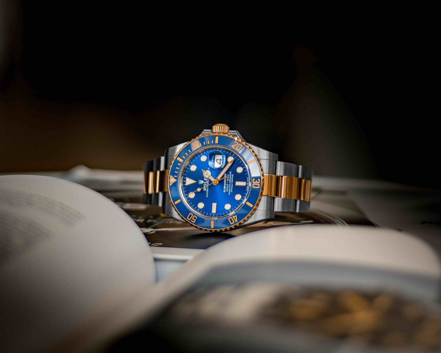 Two-tone Rolex watch with blue dial on book.