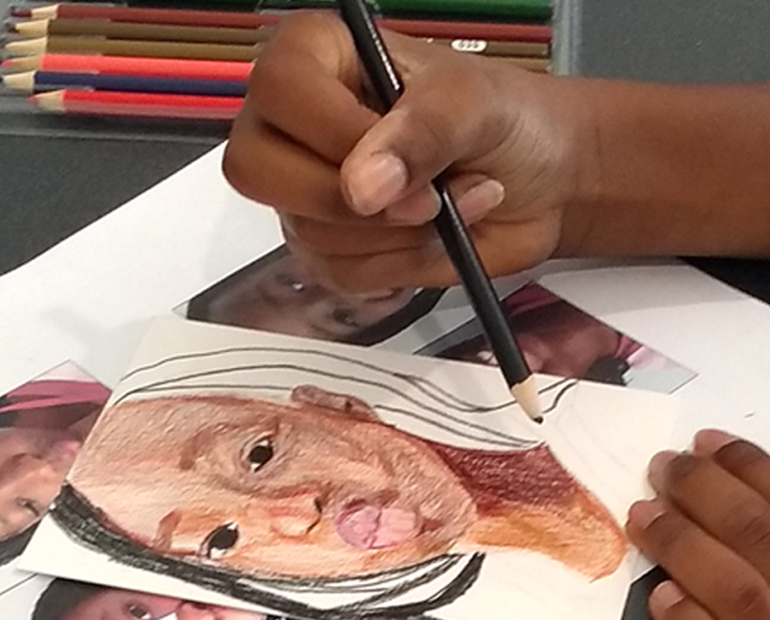 a teen holding a colored pencil and drawing a portrait of a person making a kissy face