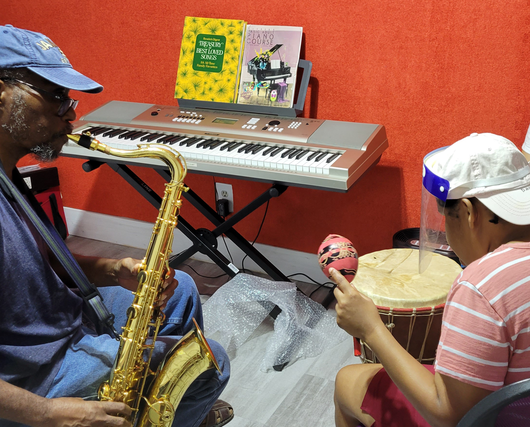 a man playing a saxophone and a woman playing playing a drum and shaking a maraca