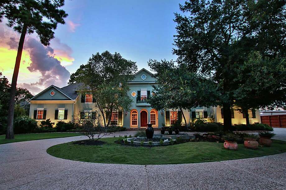 a large house with a fountain in the middle of the yard