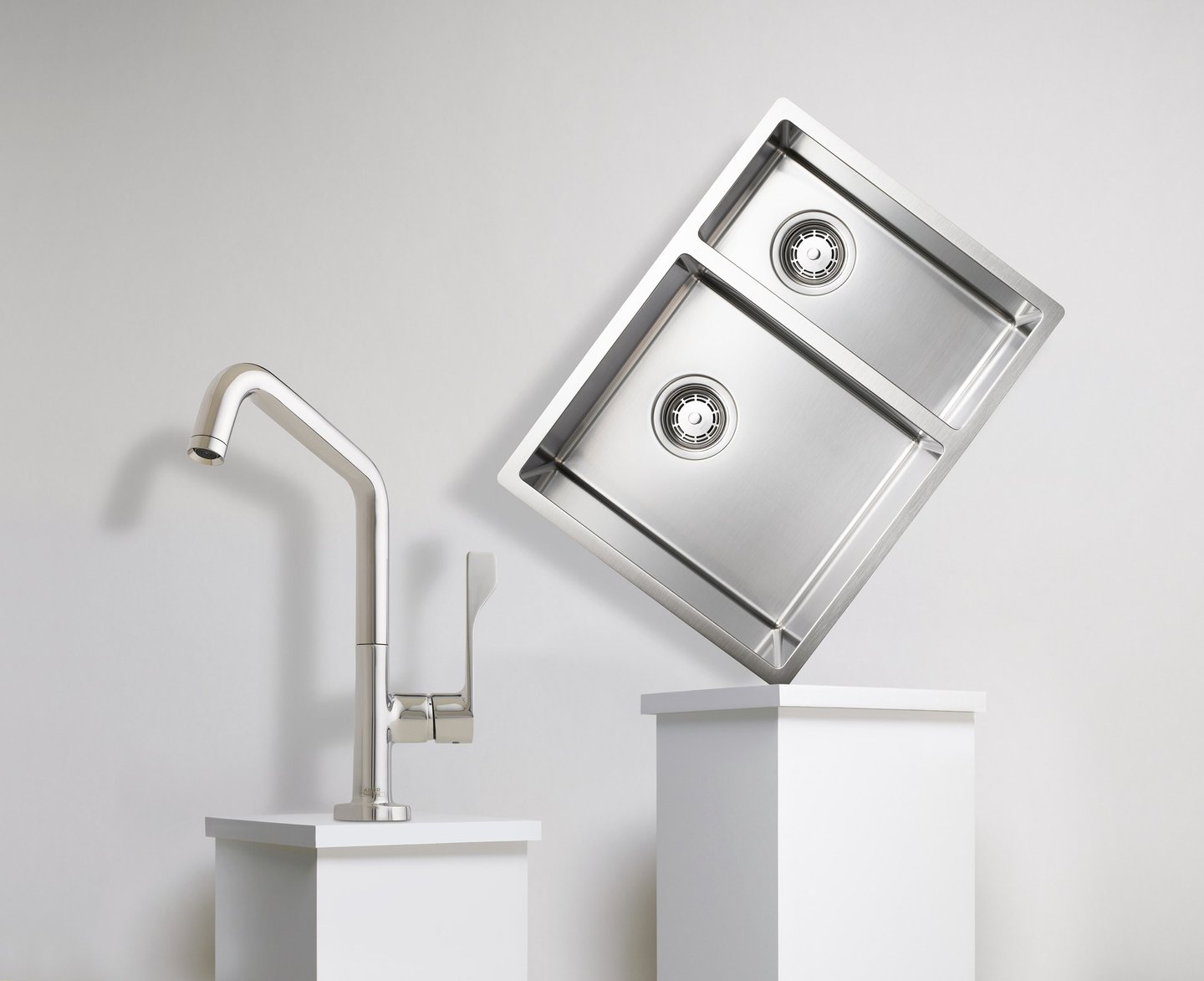 chrome kitchen tap and sink balanced on two white plinths