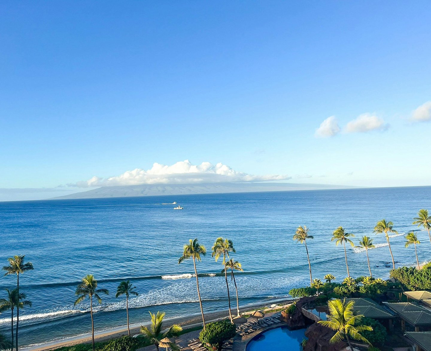 Panoramic ocean view of a tropical Maui beach resort with palm trees and blue Pacific waters.