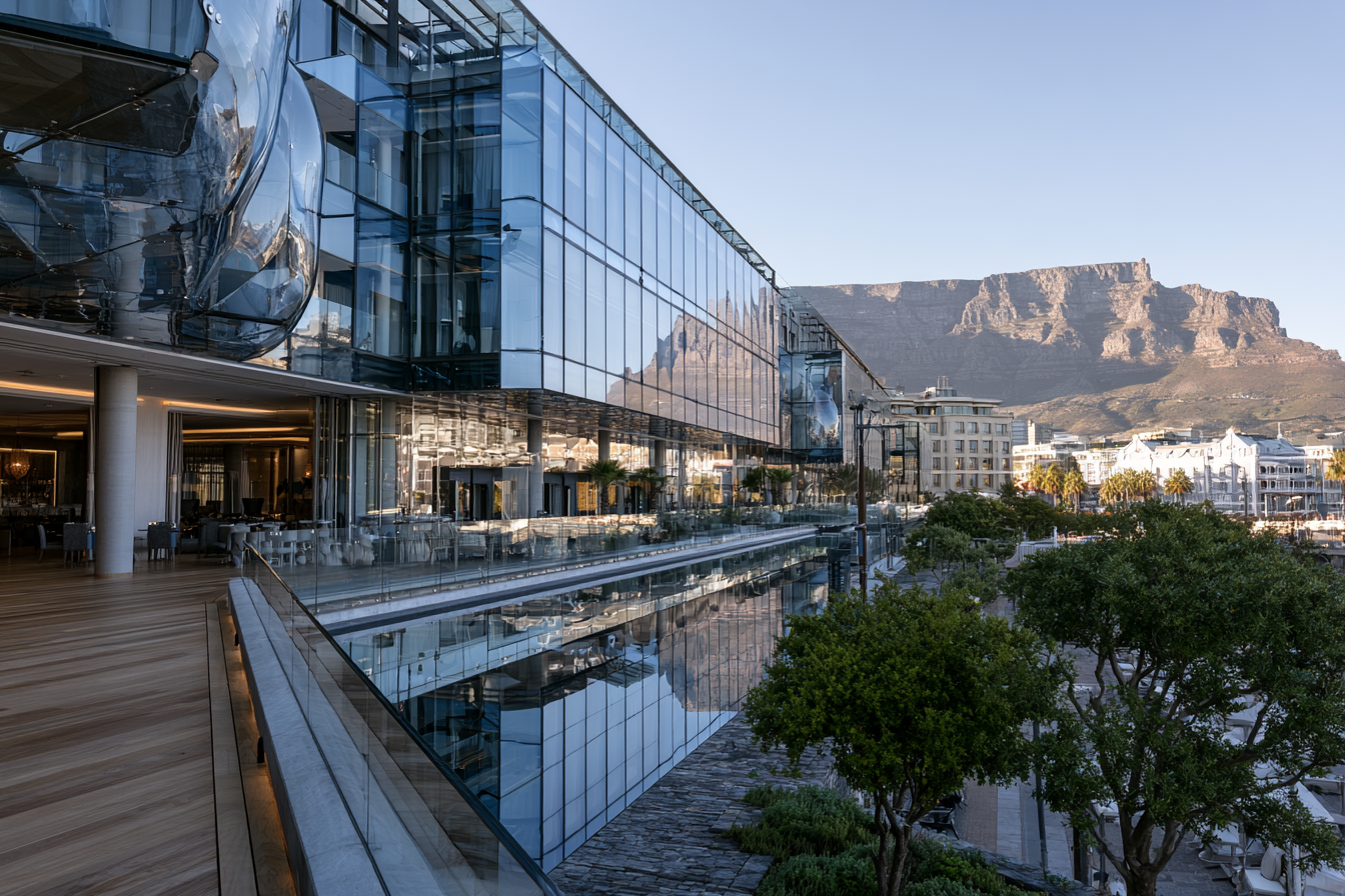 Modern glass architecture at the V&A Waterfront in Cape Town with Table Mountain in the background.