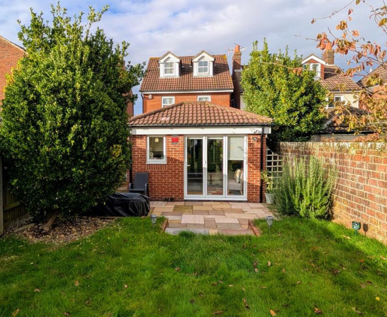 modern rear extension, stone patio, and green lawn garden.