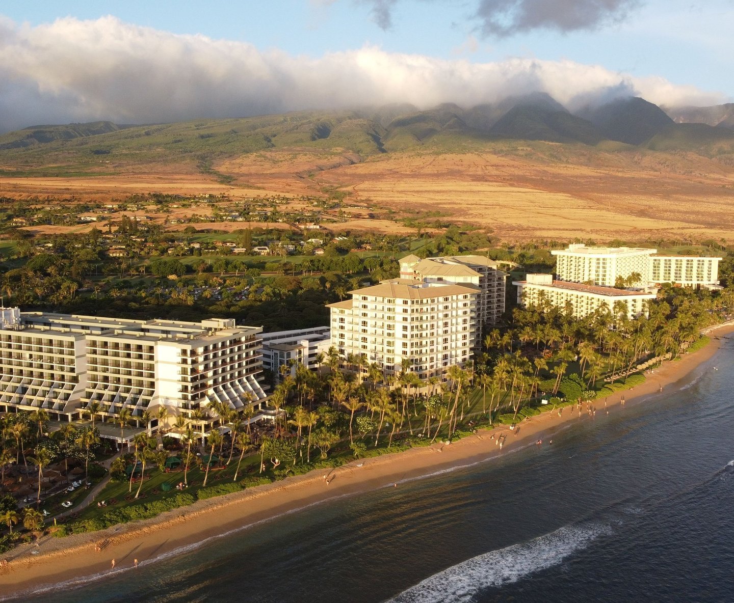 Aerial view of luxury Kaanapali beach resorts and hotels on the Maui coastline at sunset.
