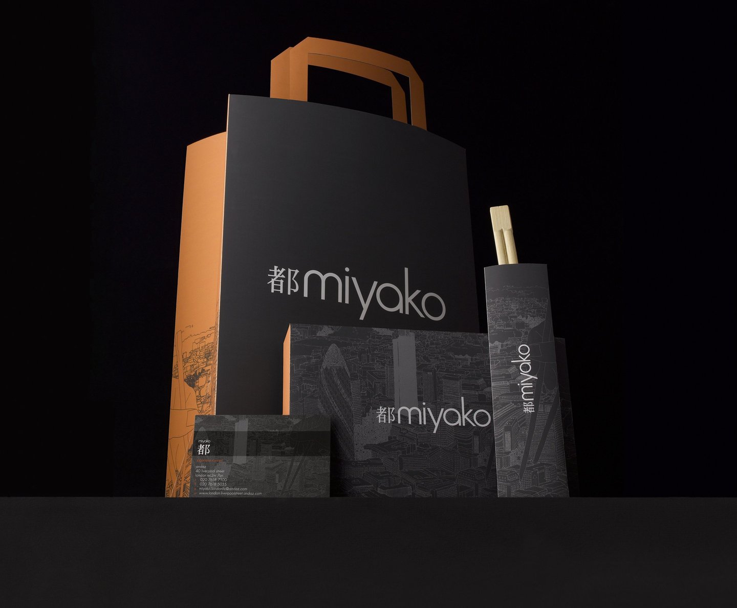 dark grey and orange paper takeaway bag menu and chopsticks on grey background 