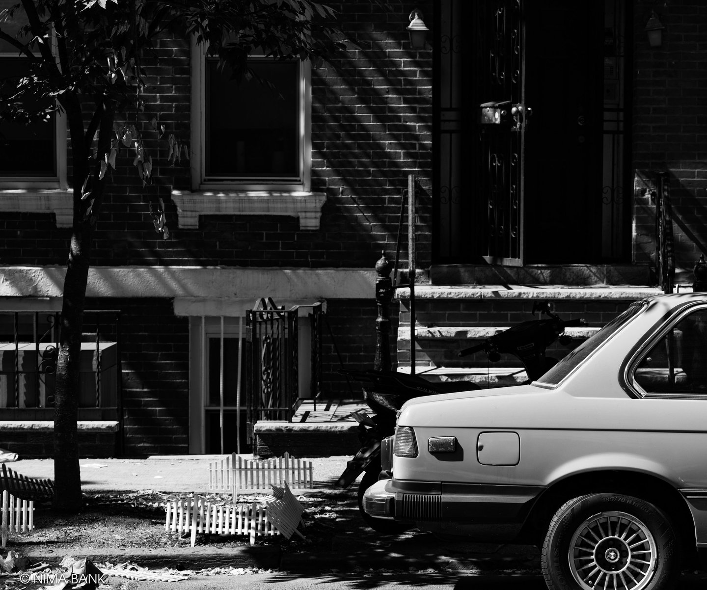 brooklyn street image of a bmw 325i parked on the sidewalk in front of a brownstone