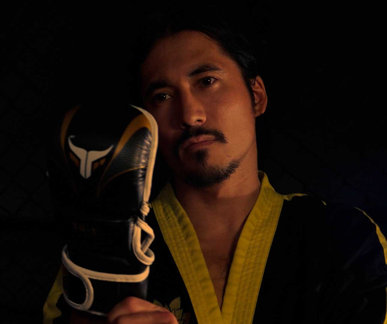 a man in a marcial arts uniform holding a pair of gloves