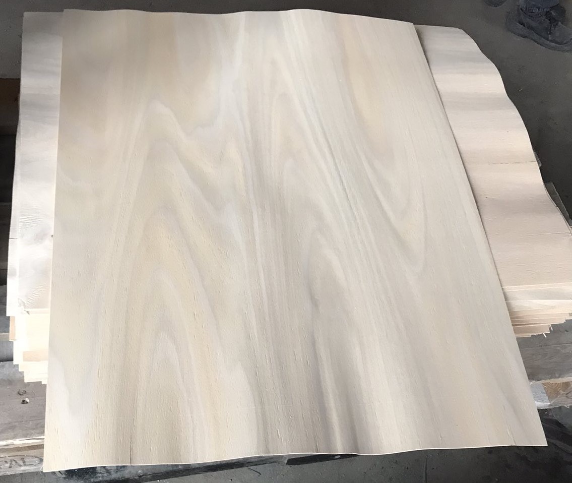 Stacked thin natural wood veneer sheets with light grain patterns for furniture making and woodworking.