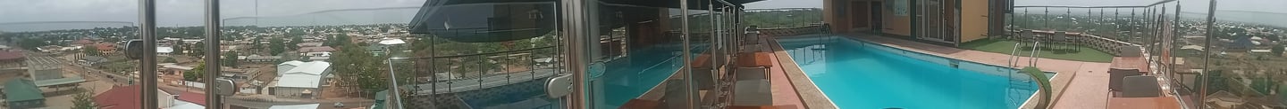a person standing on a glass wall with a pool in the background