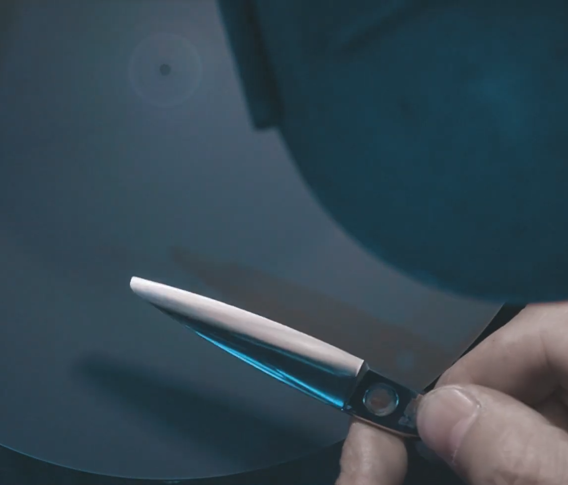 Proceso de afilado de tijeras de peluquería usando disco abrasivo de alta precisión en taller.