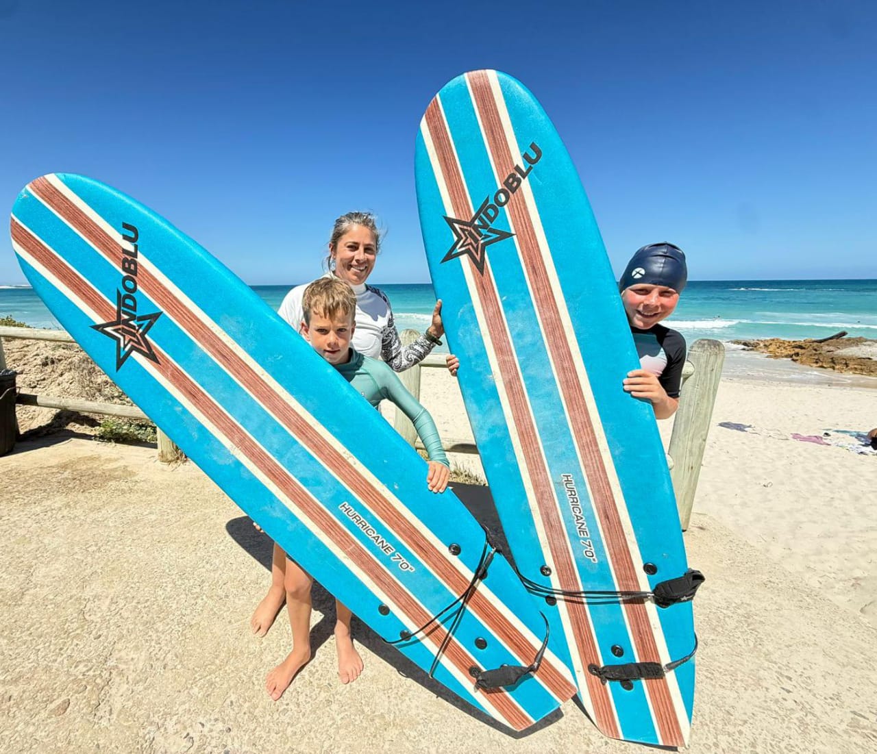 two children with surf boards and their surf and soil instructor infant of the Arniston ocean