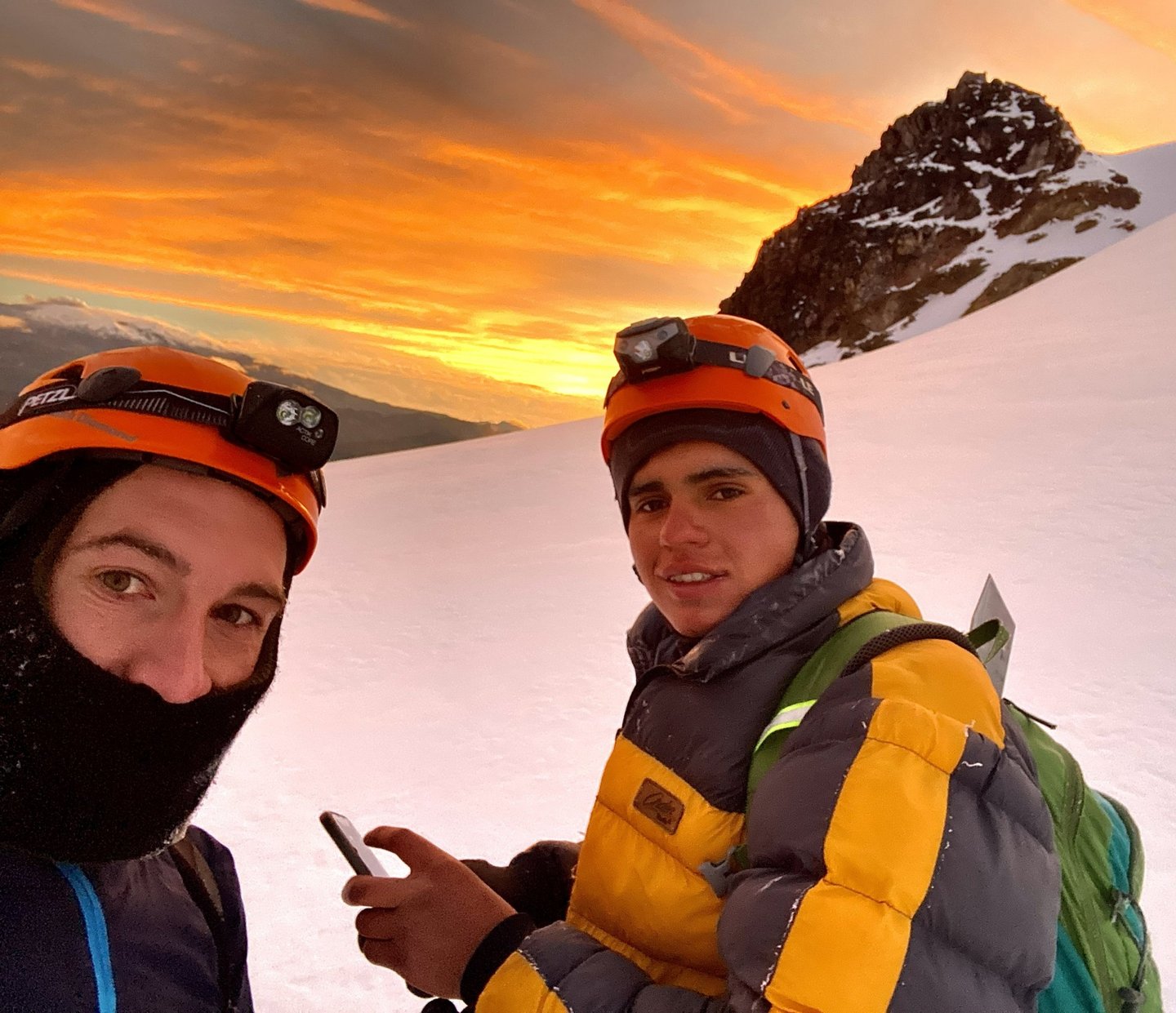 Montañistas ascendiendo en fila por la arista de roca y nieve con neblina andina.