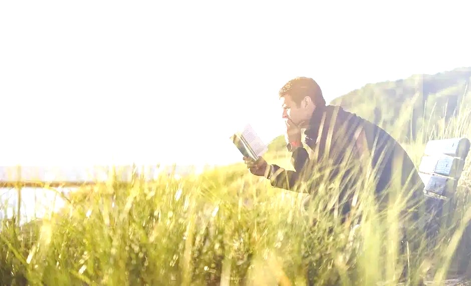 a man sitting on a bench in the grass