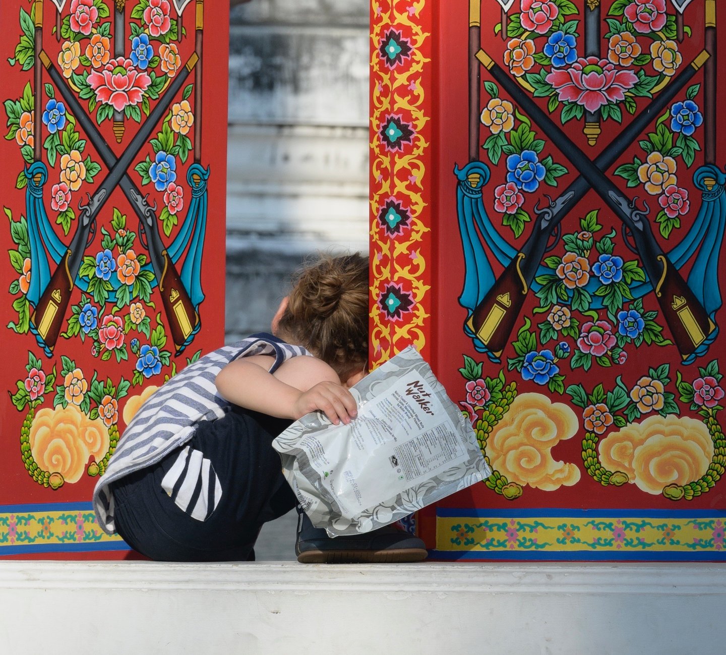 un enfant curieux regarde derrière une porte ouverte dans un temple en Thaïlande 