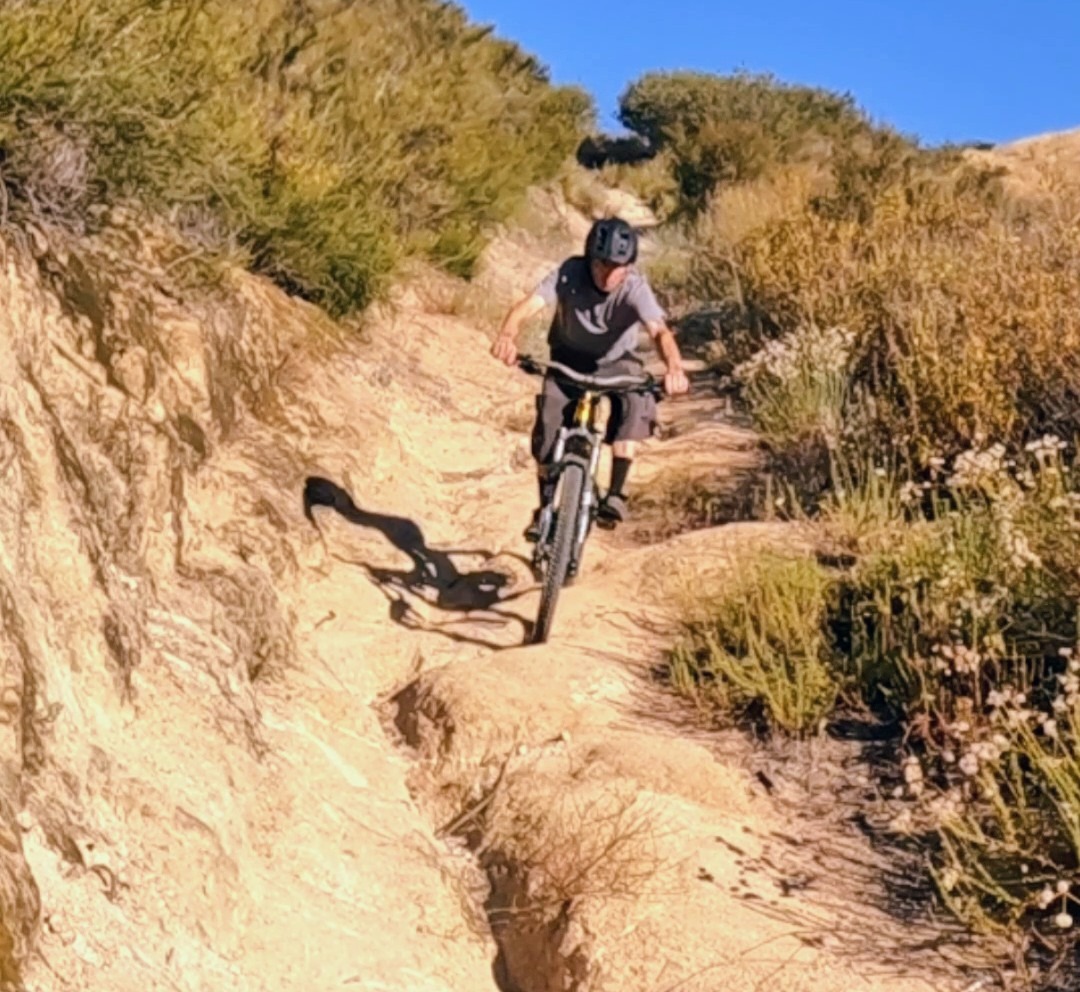 MTB rider navigating a deep rutted dirt trail section in dry Southern California terrain