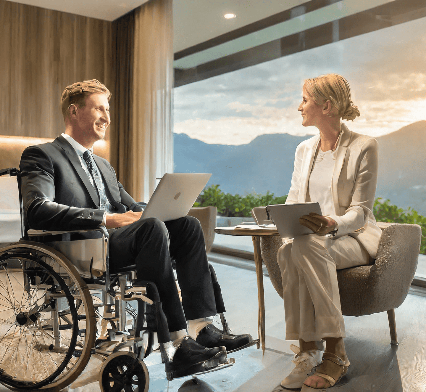 Rollstuhlfahrer sitzt einer Dame bei einem Beratungsgespräch in einem Hotelzimmer gegenüber