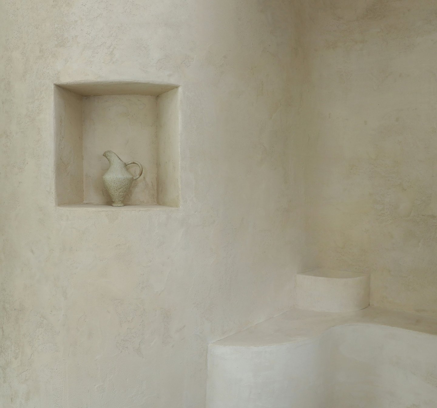 Plastered wall with an architectural niche and a handcrafted pot.