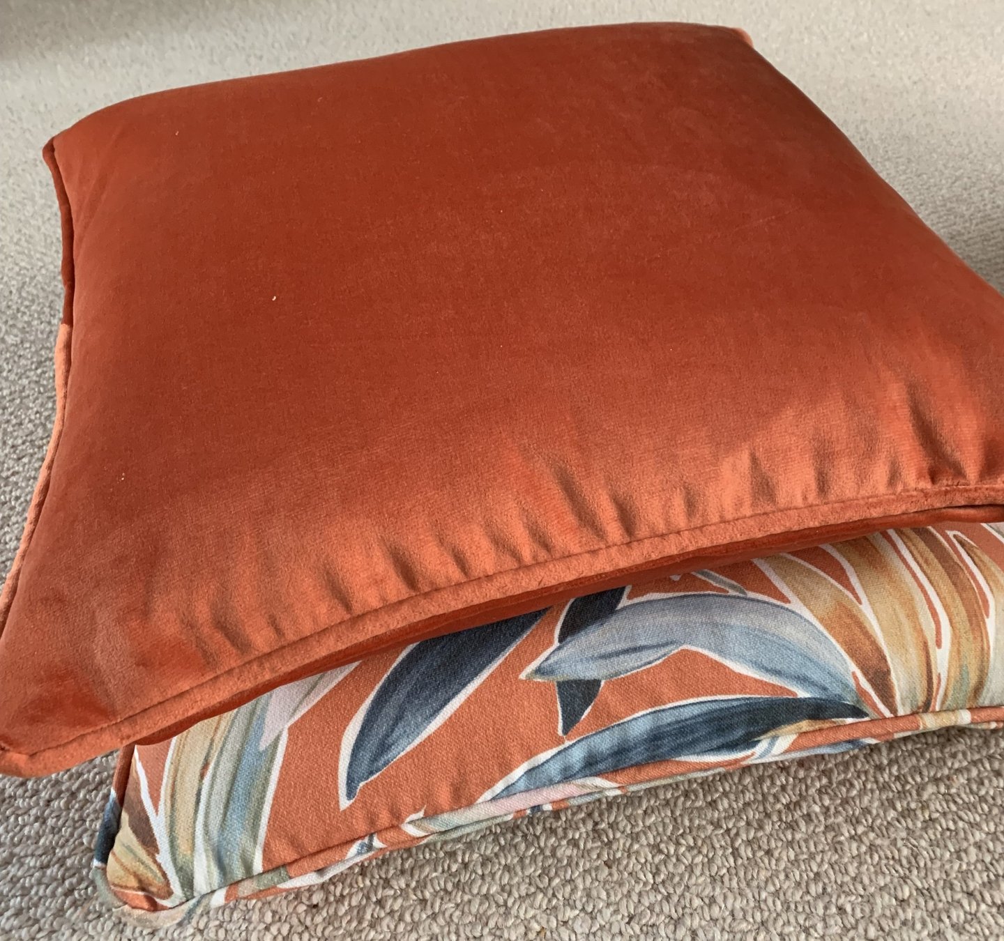 2 coordinated piped cushions with dominant colour in burnt orange