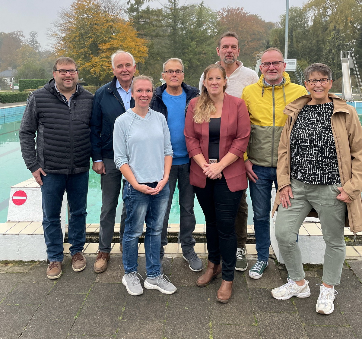 a group of people standing around a pool