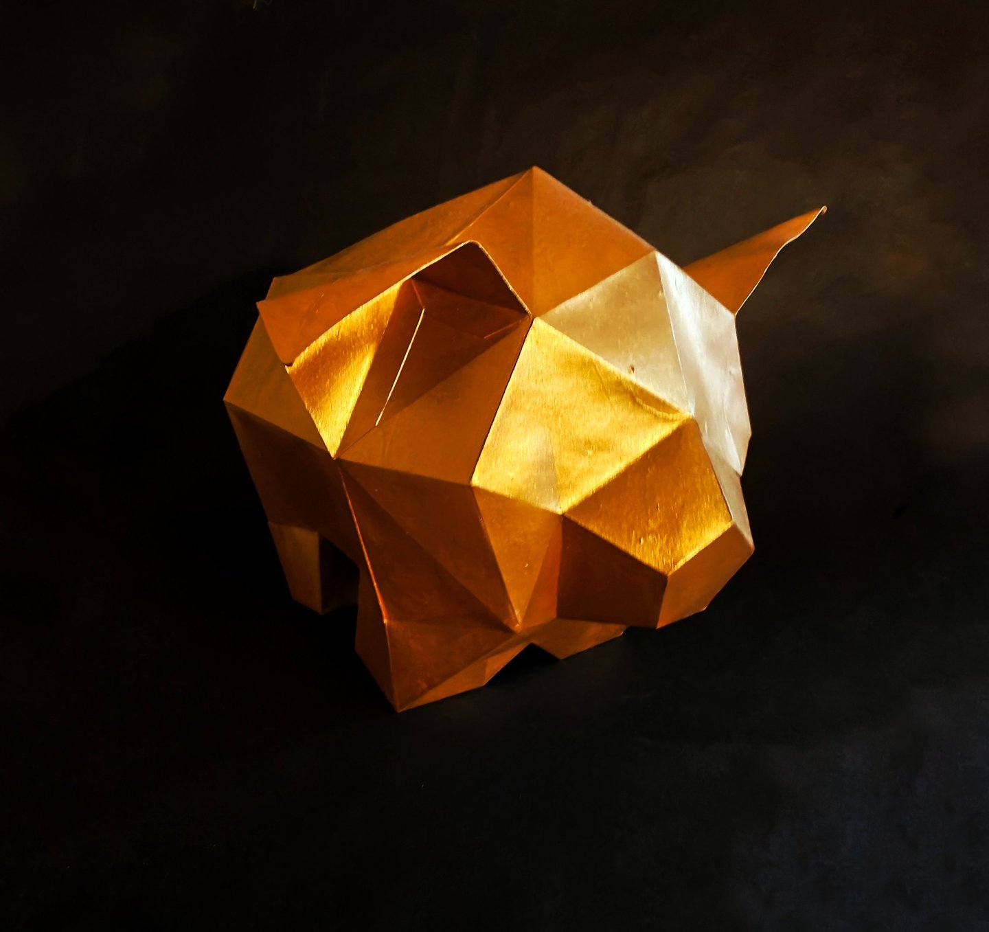 Low poly geometric gold pig sculpture on a black background for wall art or office decor.