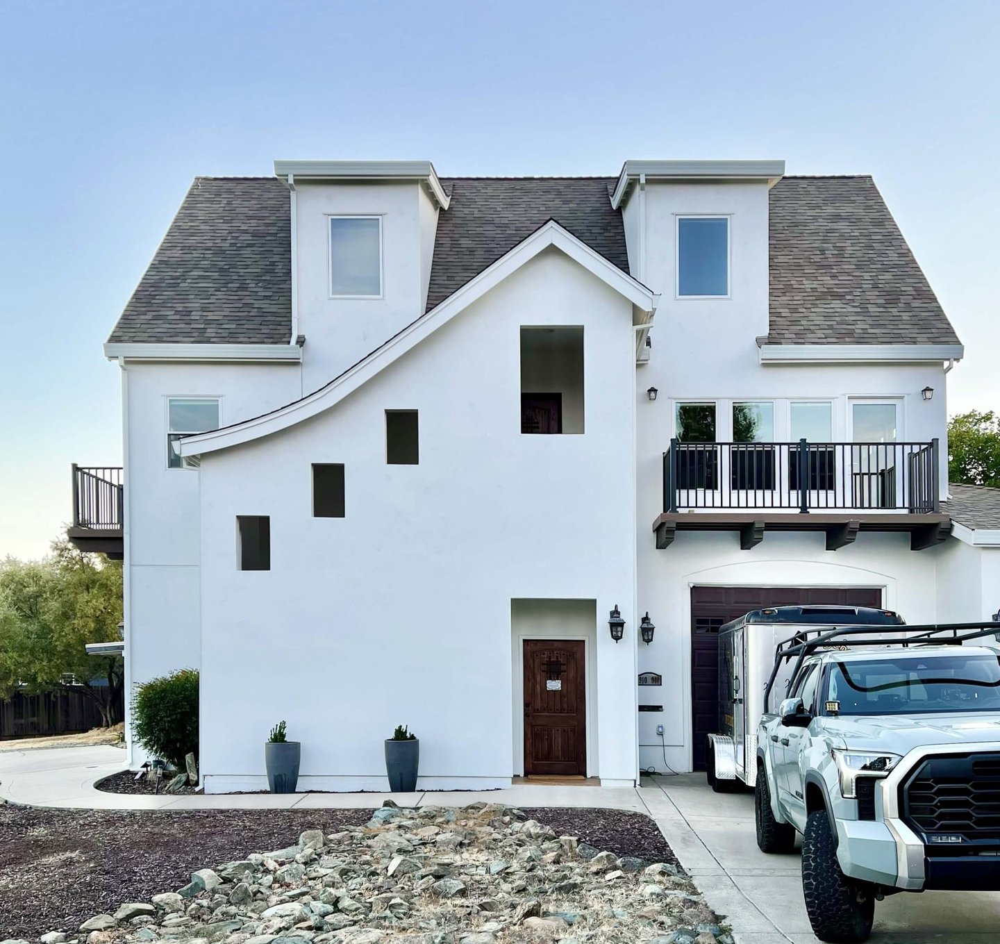 A French Revival architecture home with sloping roof lines, high dormers, and cantilevered decks.