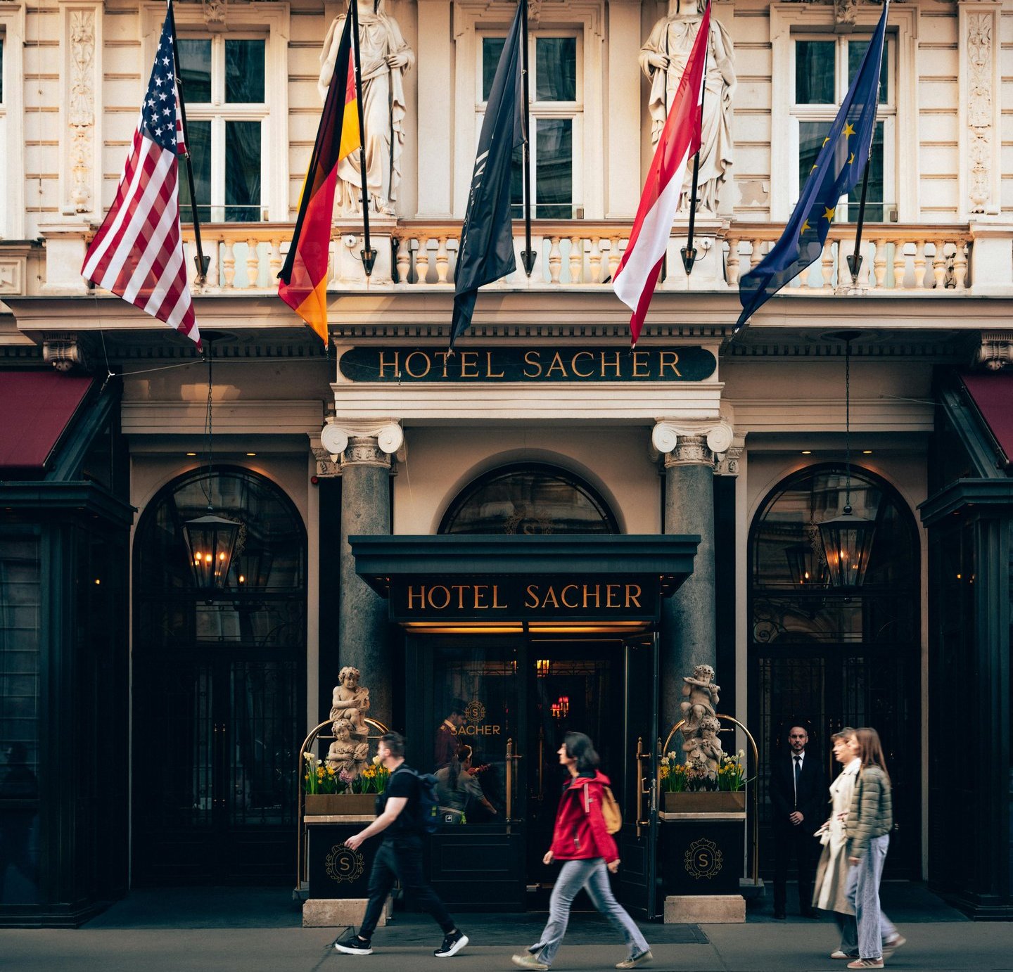 The grand entrance of Hotel Sacher in Vienna featuring historic architecture and international flags.