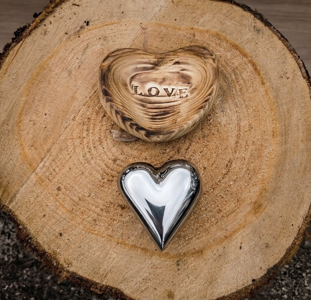 A polished metal love heart and wooden heart holder with the word LOVE stamped into it
