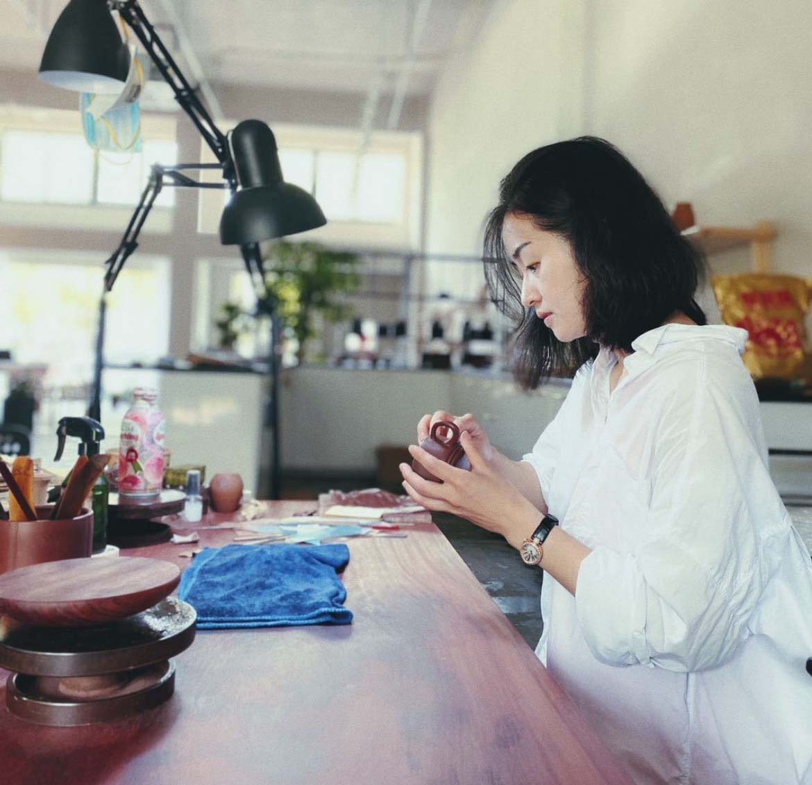 A woman holding a teapot, carefully inspecting it.