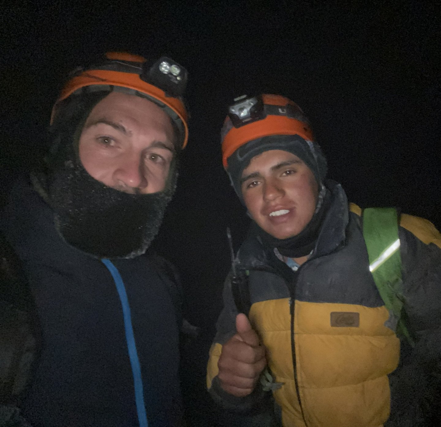 Grupo de montañistas sonriendo y abrazados en el punto de cumbre del volcán.