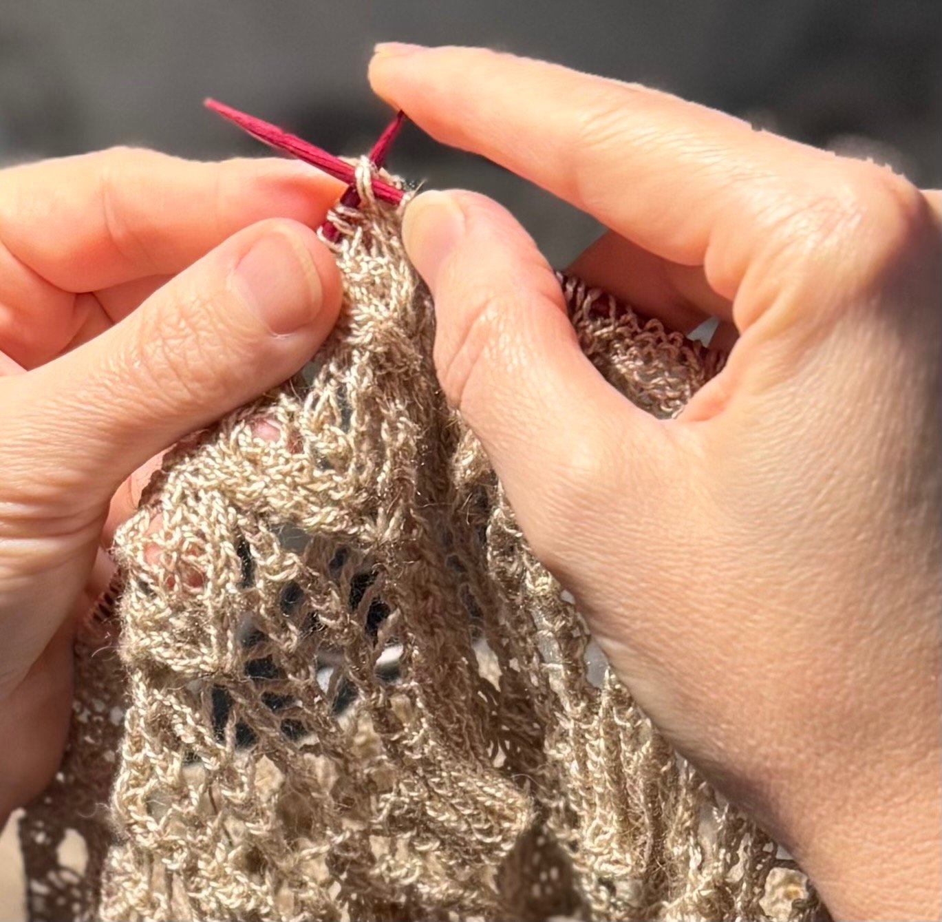A close-up image of a pair of hands working a stitch
