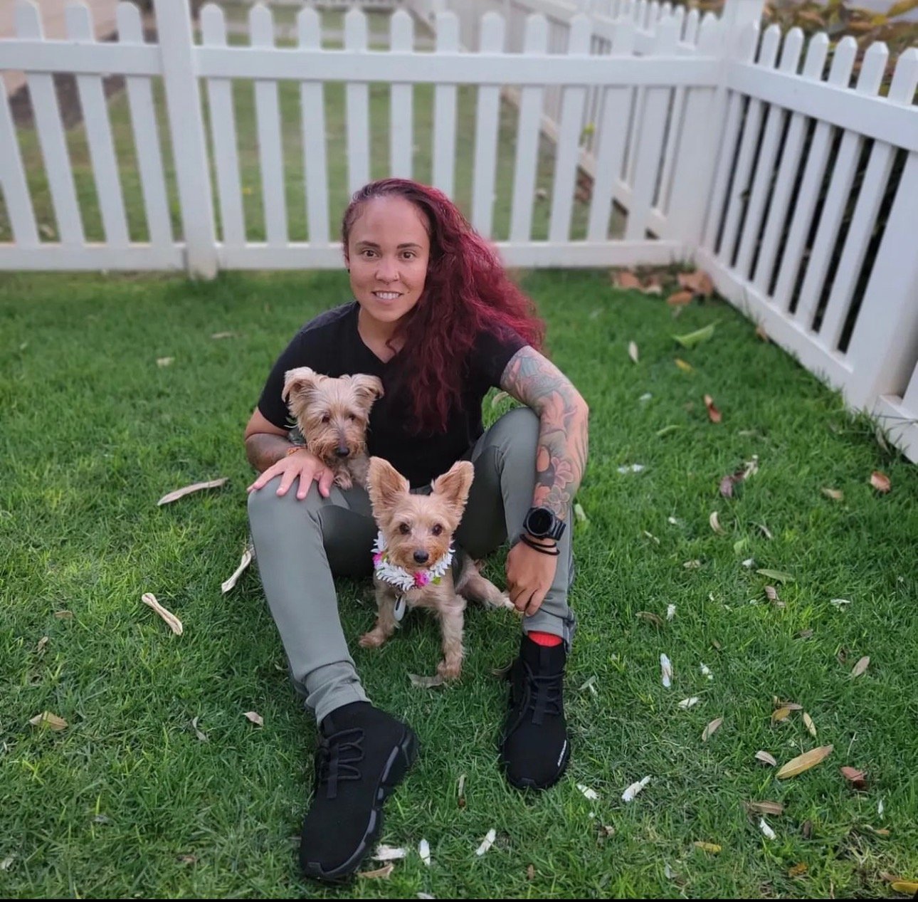 a woman sitting on the grass with two dogs